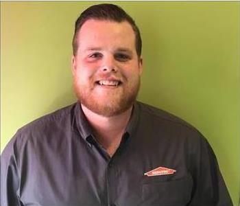 Male employee posing in front of green background