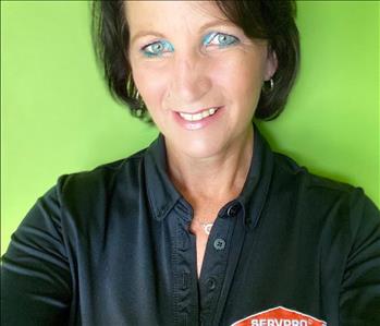 woman in black shirt with black hair infront of green wall