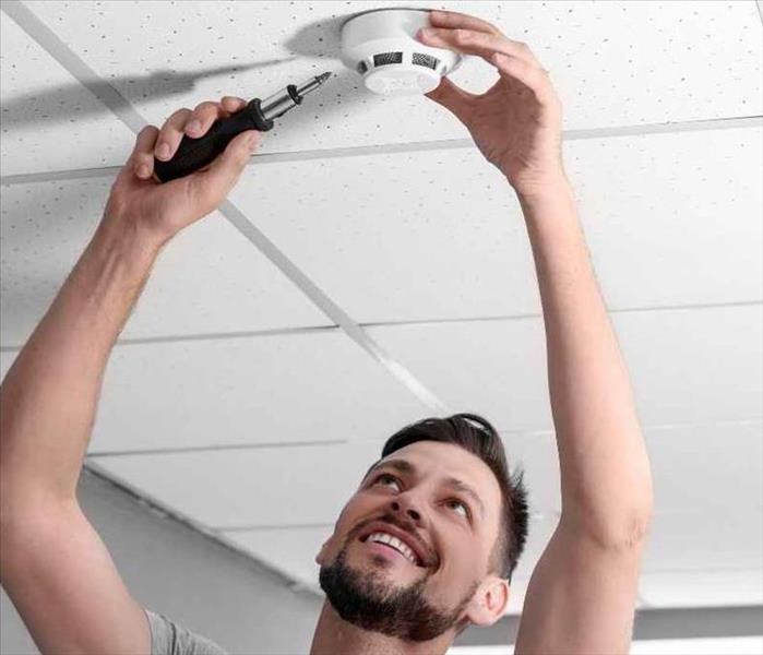 A man changing the battery in his smoke detector