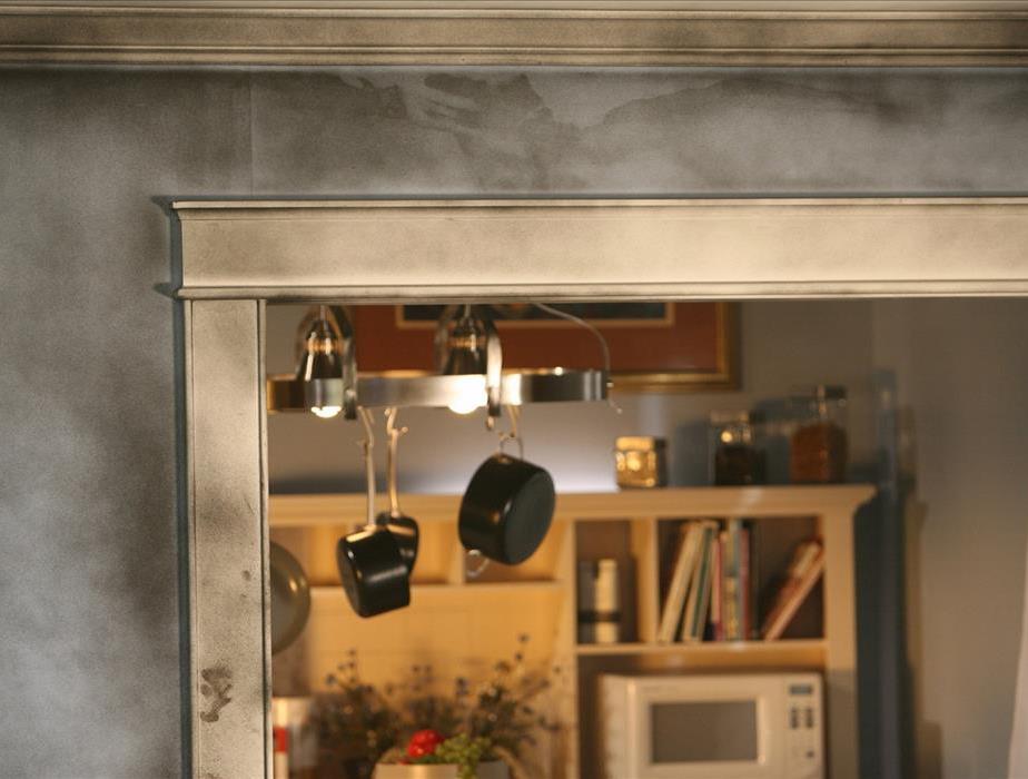gray walls with ivory molding covered in black soot - two pots hanging in front of bookcase with white microwave and books