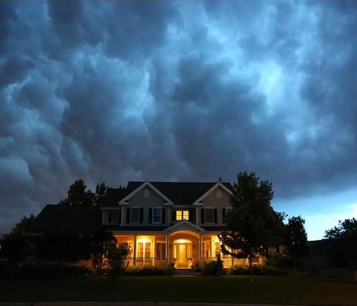 A house with the lights on underneath a dark stormy sky